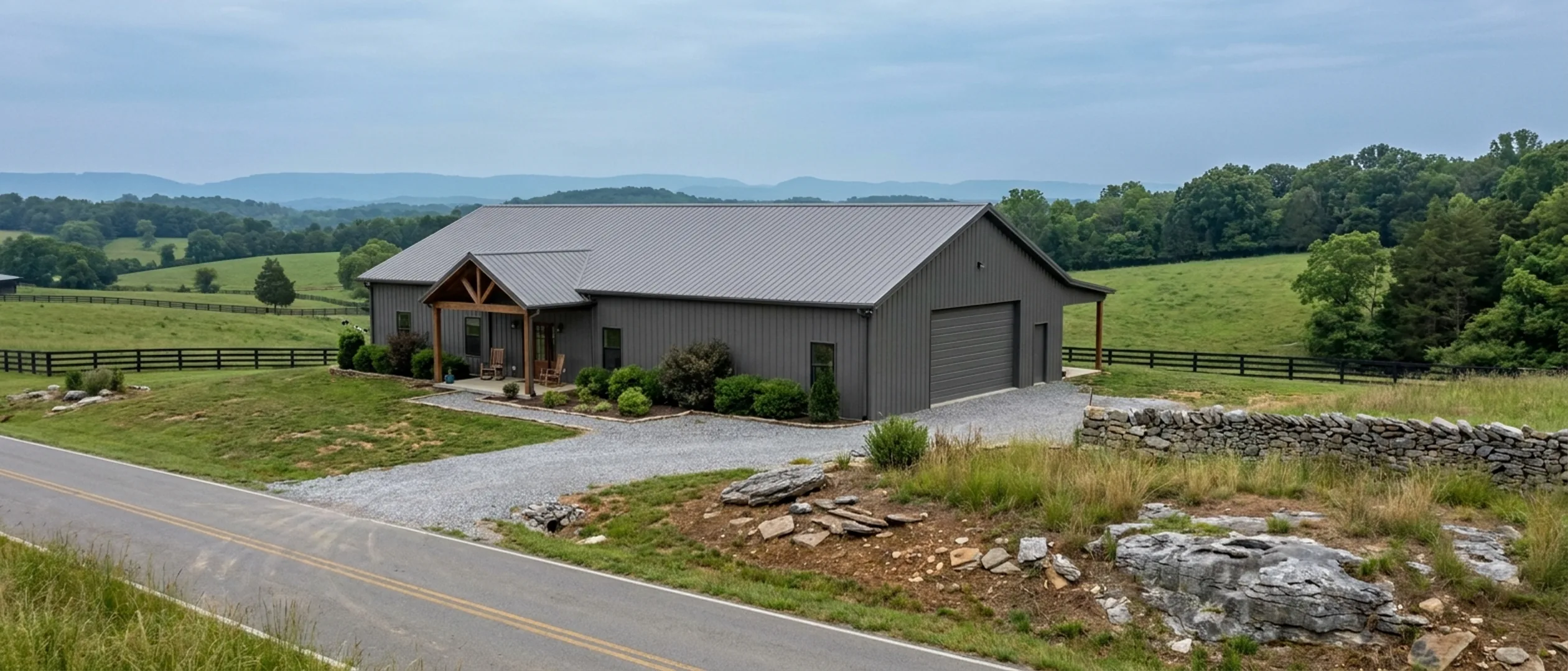 A completed barndominium with a covered entry porch and an attached shop bay, photographed in flat overcast daylight.